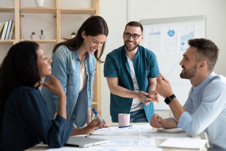 Smiling diverse colleagues gather in boardroom brainstorm discuss financial statistics together